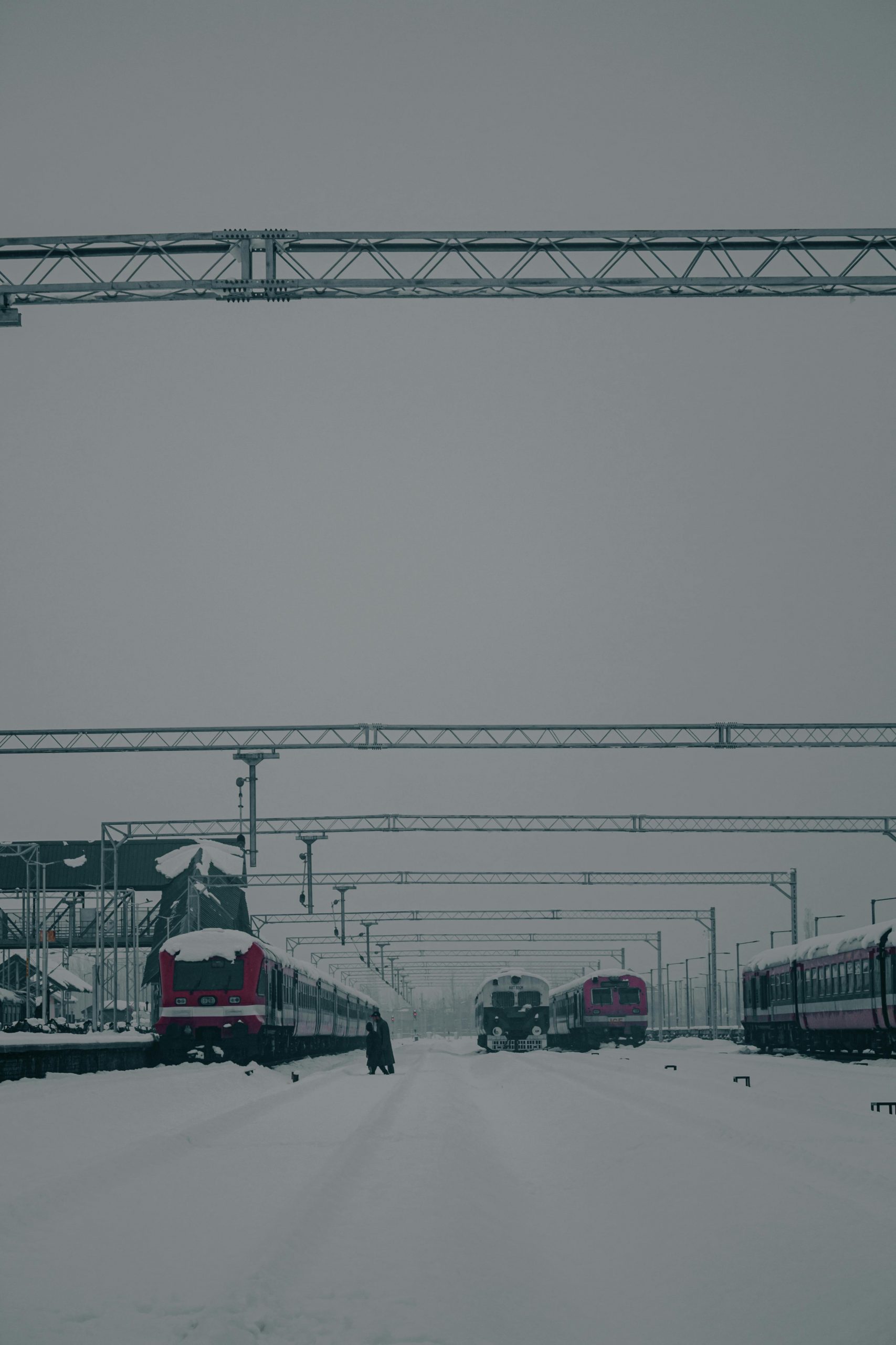 A serene winter scene of snow-covered trains at a station, showcasing a calm winter travel moment.