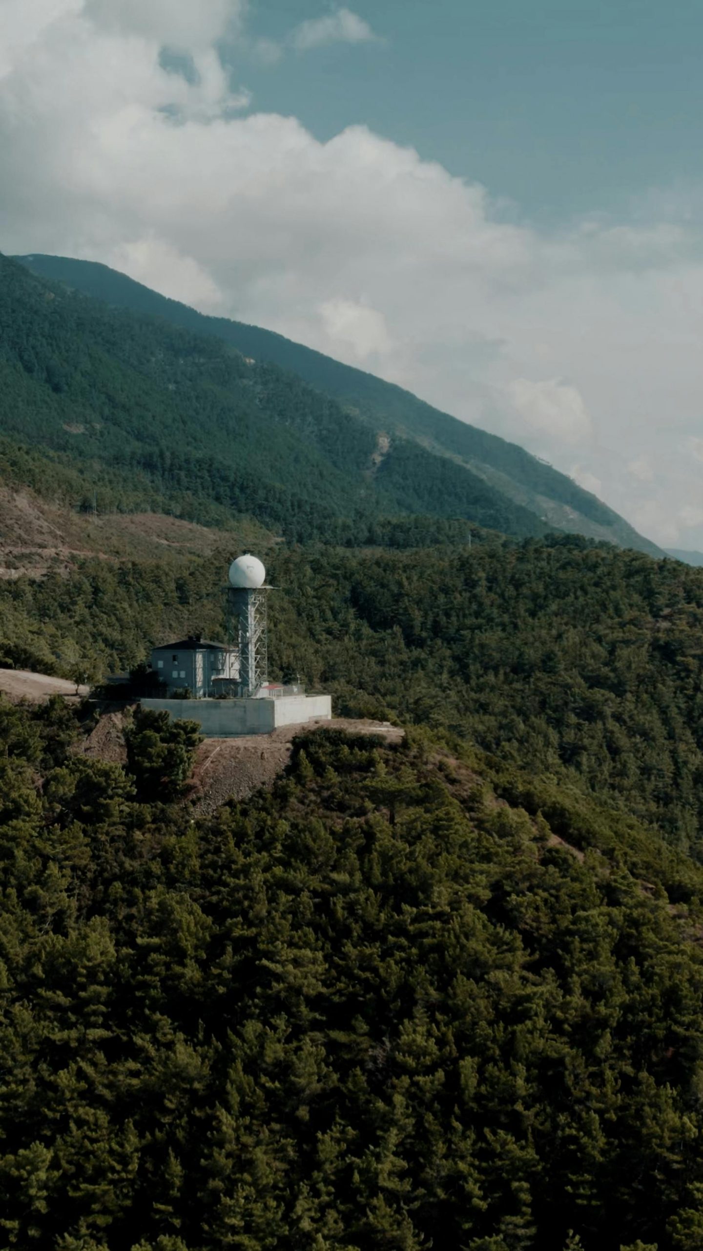 A weather station overlooking lush forests in the Turkish mountains offers a stunning landscape view.