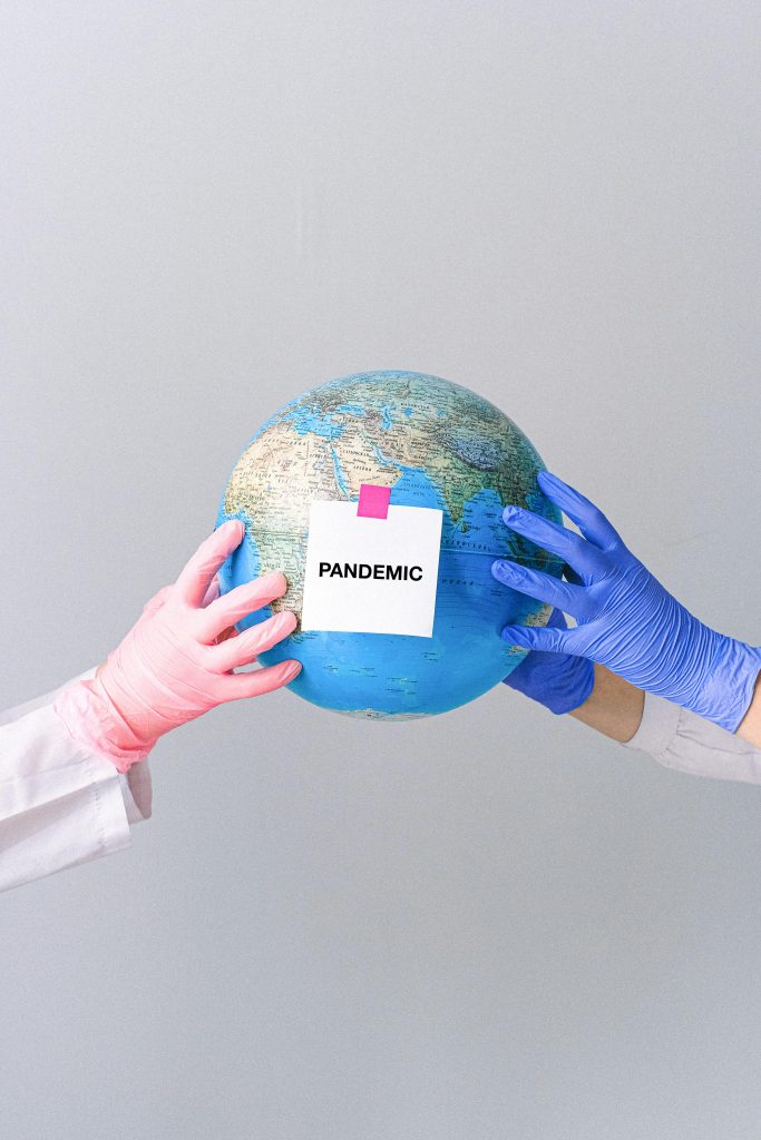 Gloved hands holding a globe with 'Pandemic' text, symbolizing global health crisis.